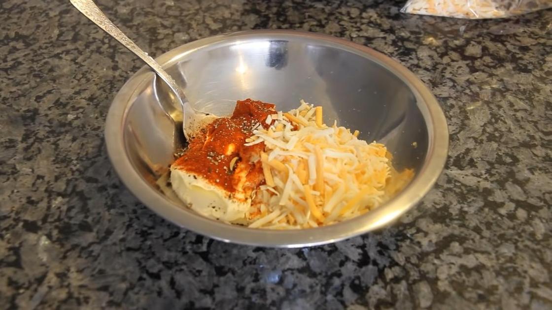 В миске на столе тертый сыр, сметана, паприка