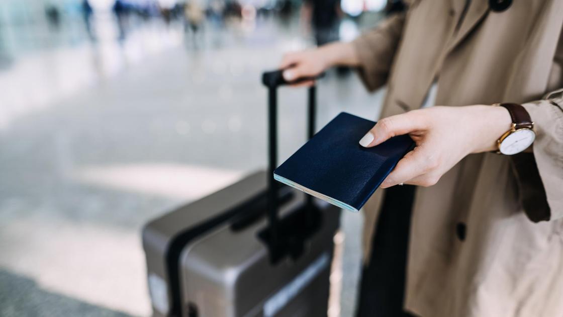 Женщина с чемоданом держит паспорт