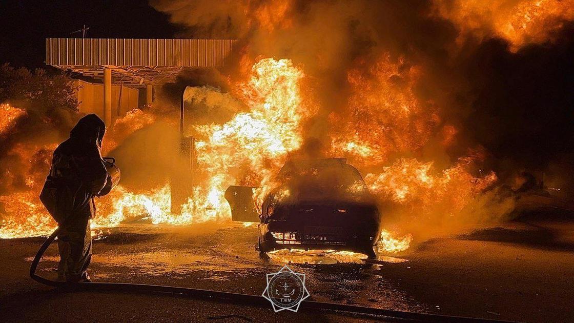 Пожарный тушит автомобиль на АЗС