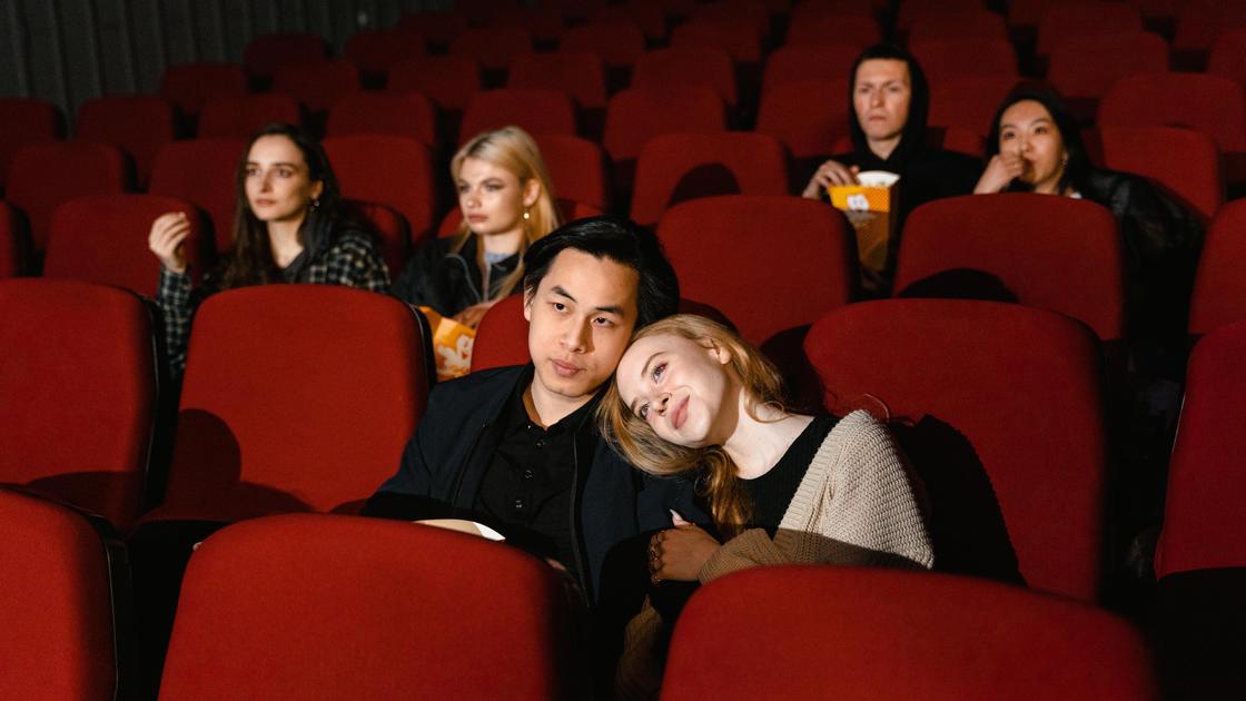 молодая пара смотрит фильм в кинотеатре.