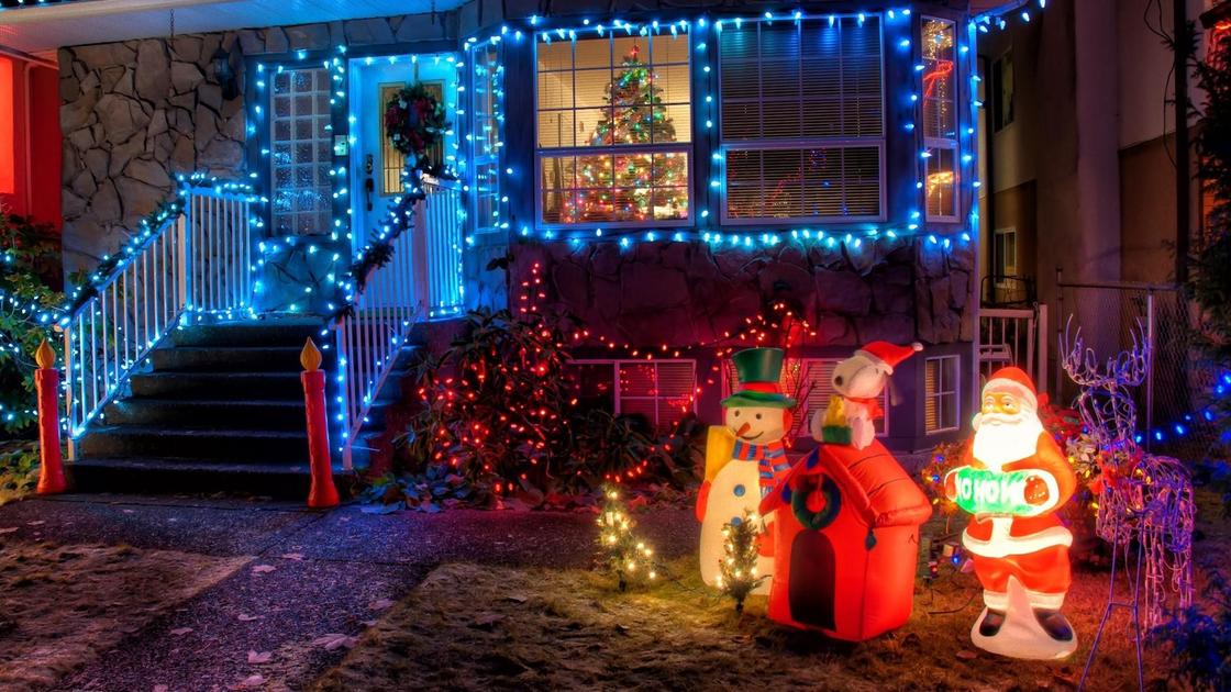 Дом украсили светящимися голубыми светодиодами, а кусты, елочки рядом с крыльцом светятся красными огоньками. Рядом с крыльцом стоят светящиеся фигурки Санта Клауса, снеговика и надувной домик.