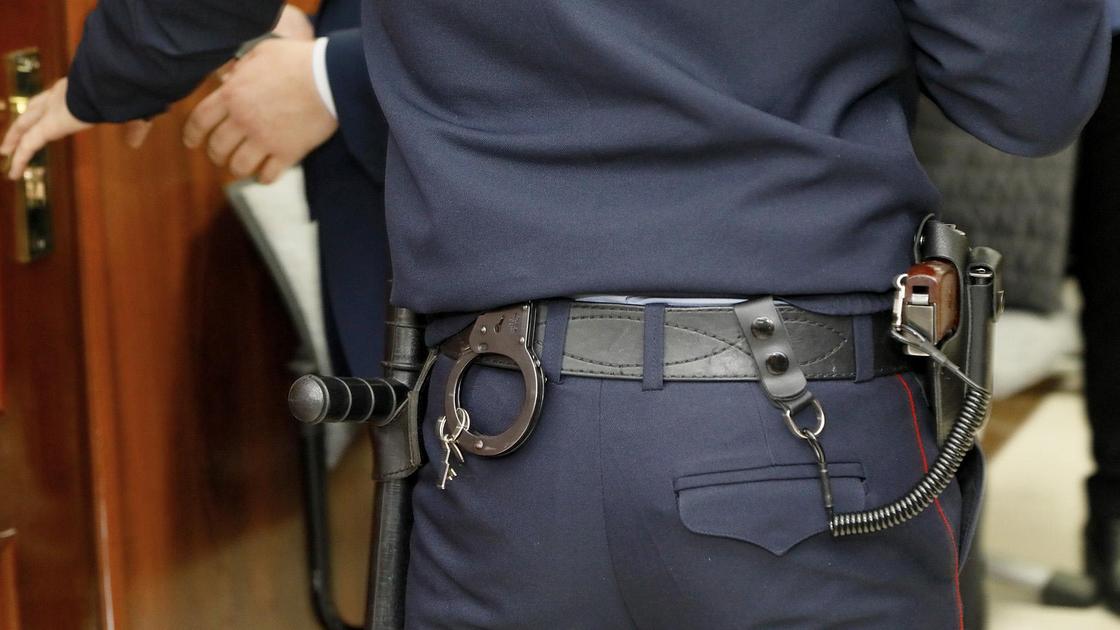 Полицейский с наручниками, дубинкой и оружием на поясе