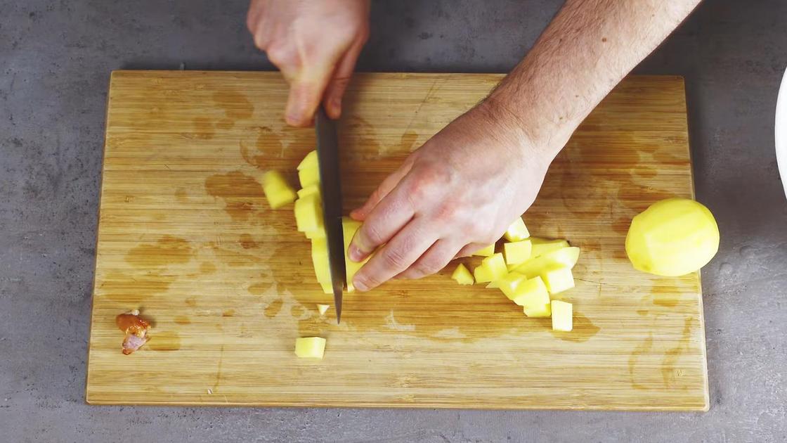 Картофель нарезают кубиком на разделочной доске