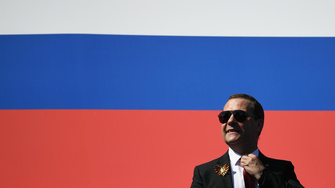 Дмитрий Медведев на фоне российского флага