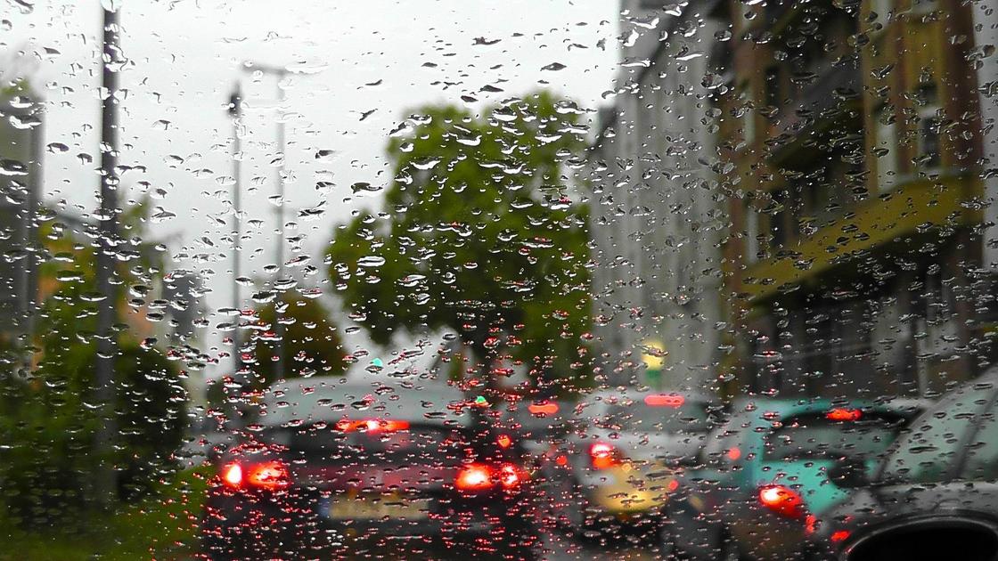 Автомобили на дороге на фоне стекла с каплями дождя