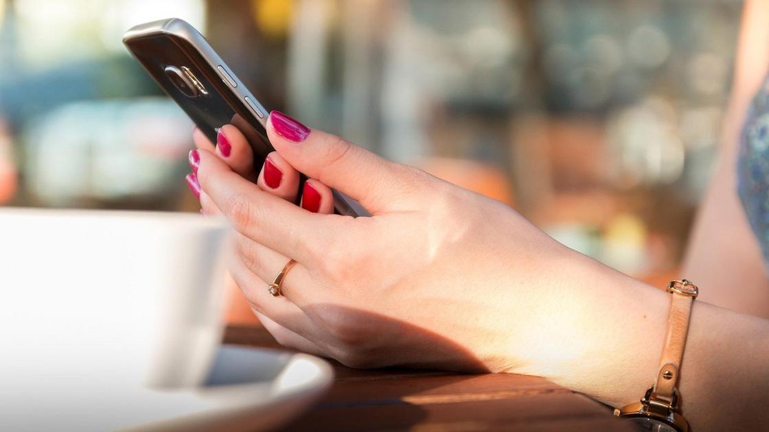 Смартфон ұстап отырған әйел