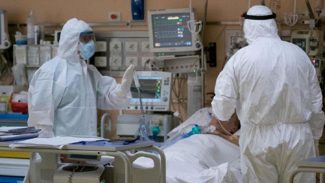 Врачи проверяют состояние пациента, лежащего на больничной койке