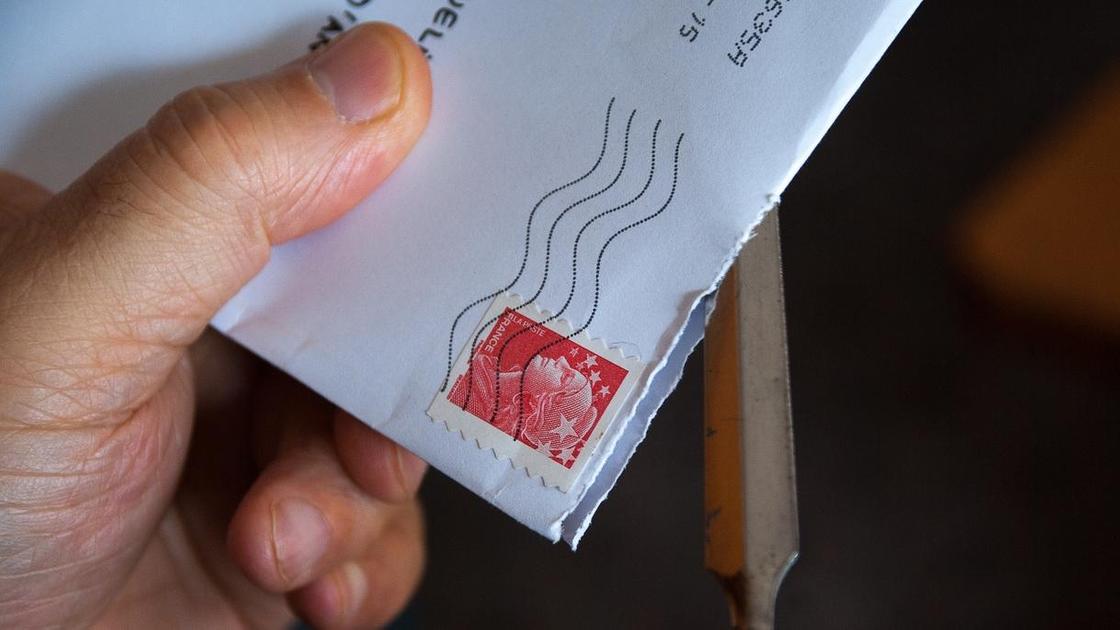 Человек вскрывает конверт с письмом