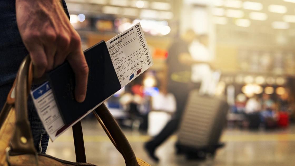 Билет на самолет и сумка в мужской руке