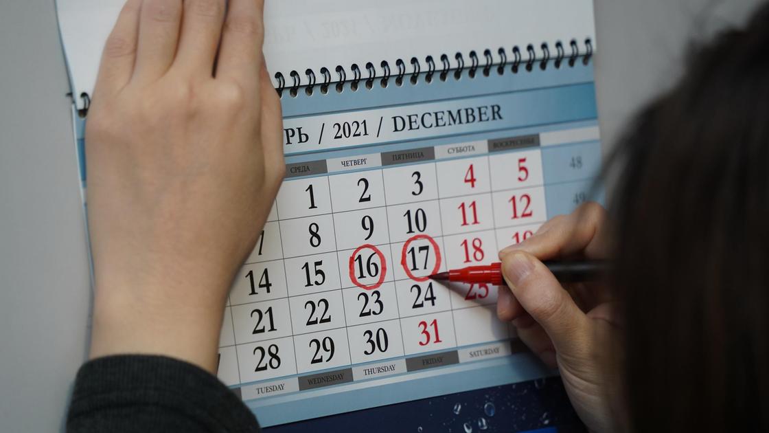 Девушка обводит дату в календаре