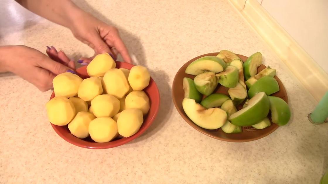 Нарезанные дольками яблоки в тарелке и очищенный картофель в тарелке