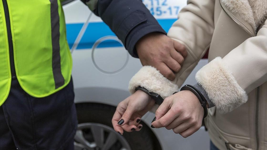 Полицейский держит за руку задержанную