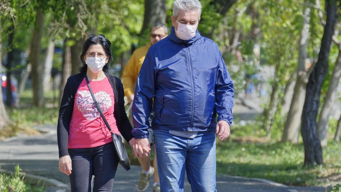 мужчина и женщина в масках идут по улице