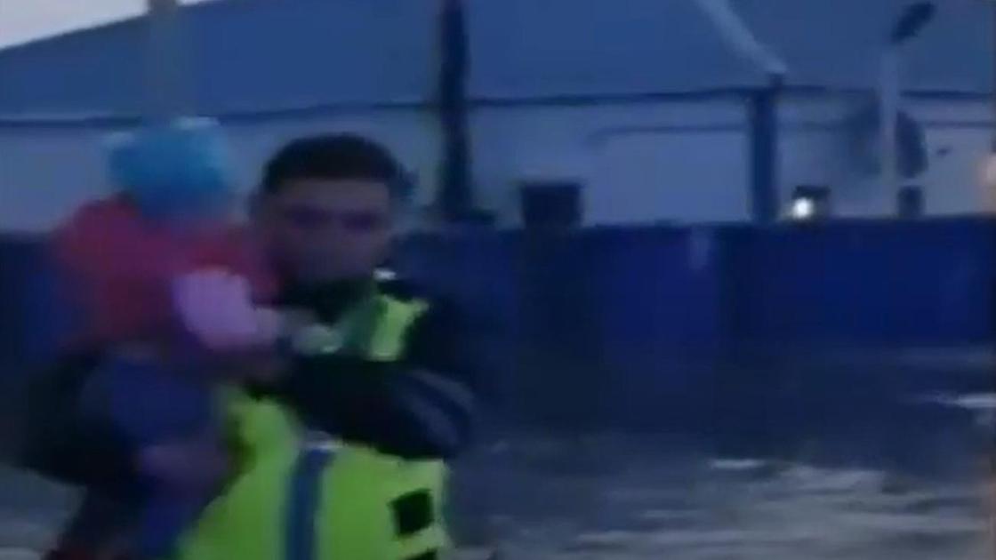 Полицейский выносит на руках ребенка из подтопленного дома в Атырауской области