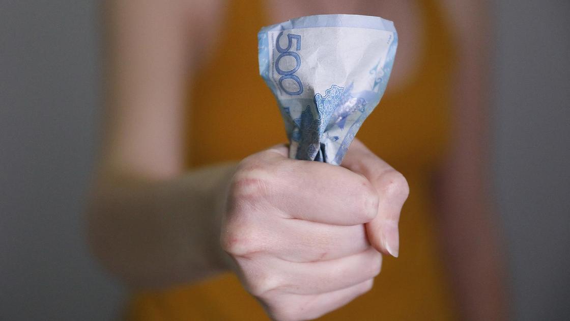 Женщина сминает банкноту в руке