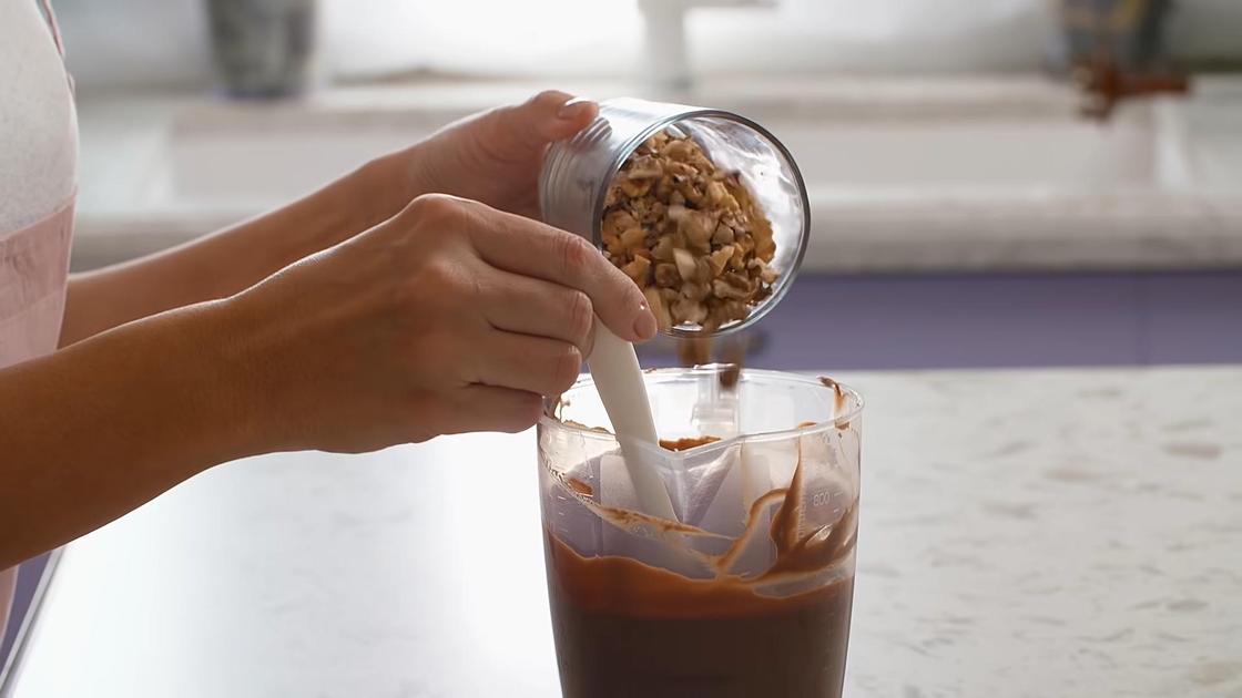 Орехи пересыпают в стакан с шоколадной глазурью