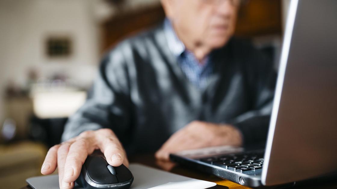 Пожилой мужчина сидит за компьютером