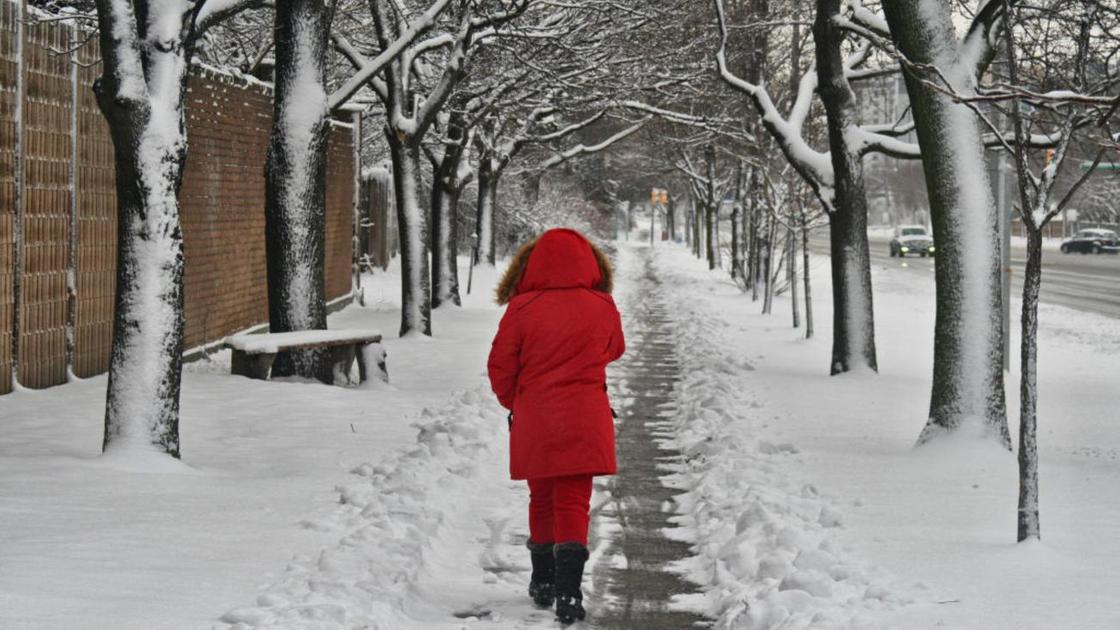 Женщина в красной куртке идет по улице