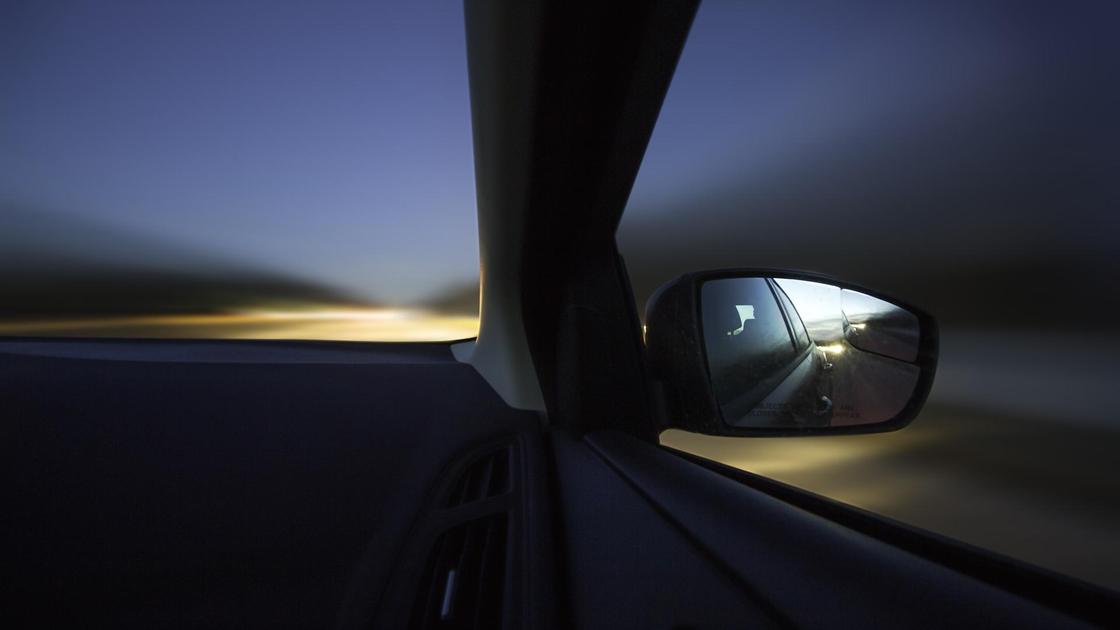 Автомобиль изнутри, свет от фар на дорогу, отражение в зеркале бокового вида