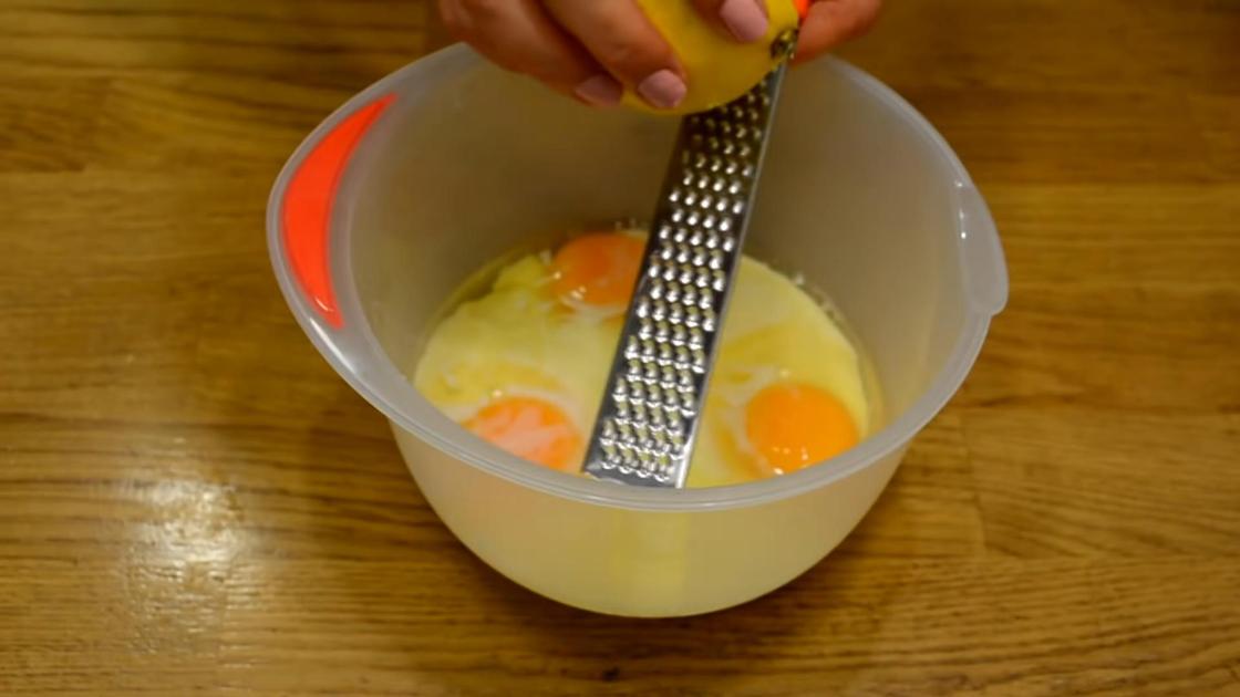 Цедру лимона трут на терке над миской с куриными яйцами и сгущенным молоком