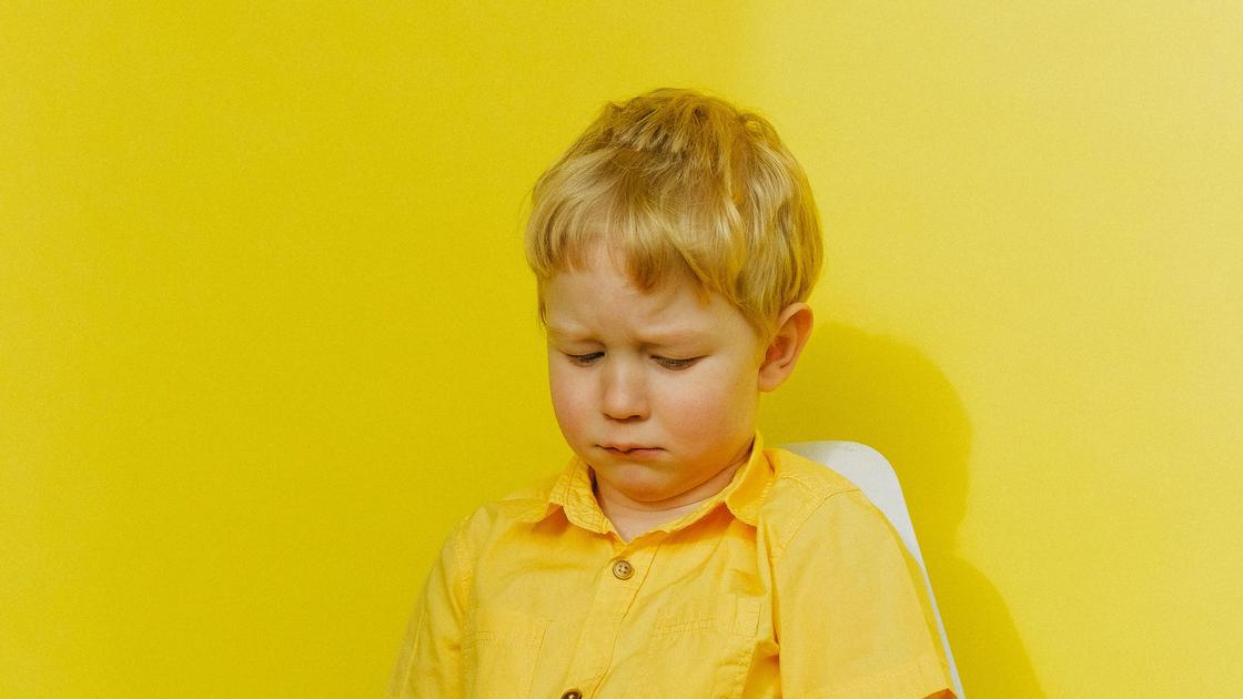 Мальчик в желтом сидит на стуле