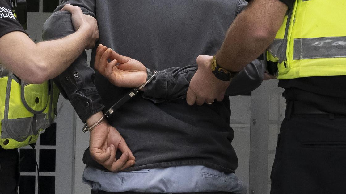 Задержанного мужчину в наручниках ведут полицейские