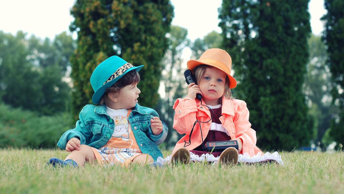 Дети в шляпах сидят на траве