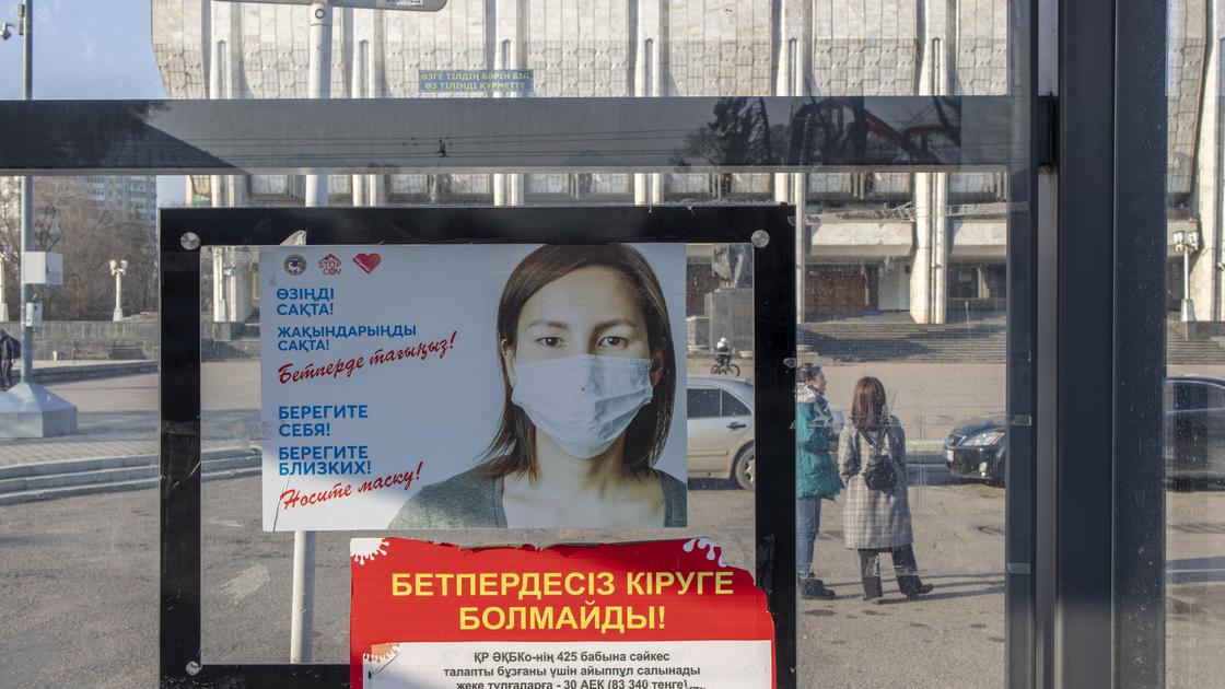 баннер с девушкой в маске висит на улице в Алматы