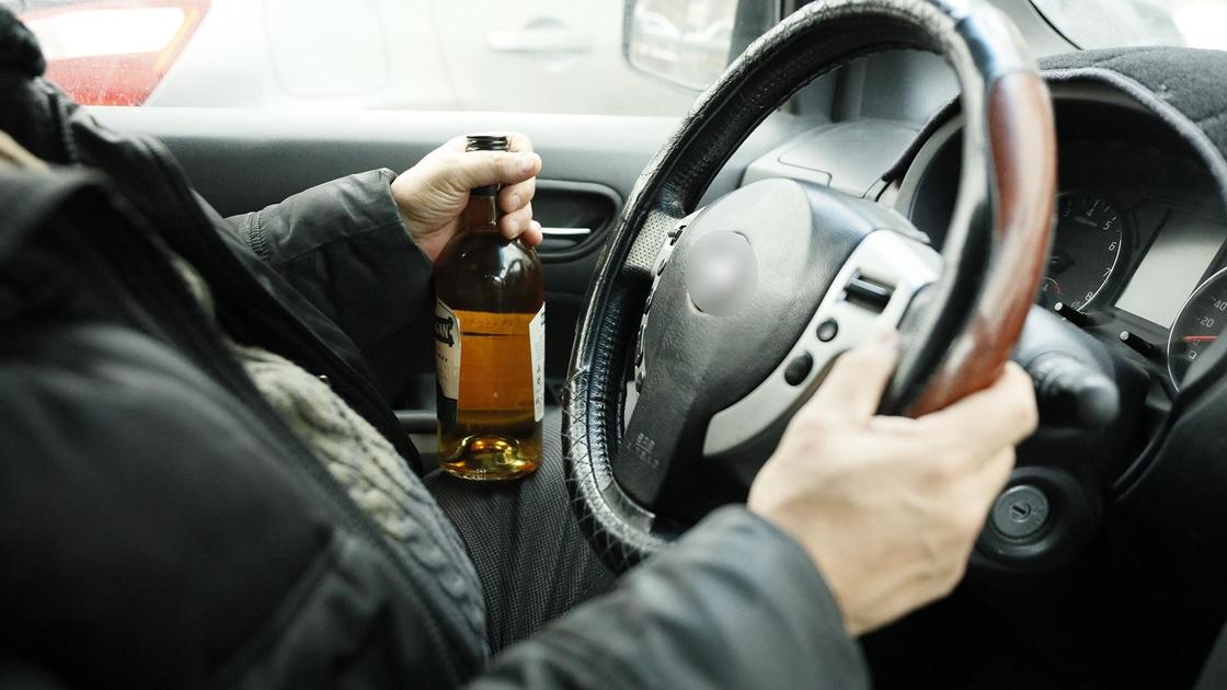 Водитель держит виски за рулем