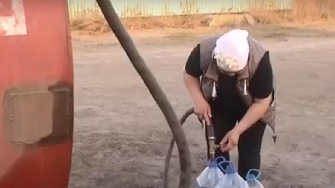 Женщина набирает воду в бутылки