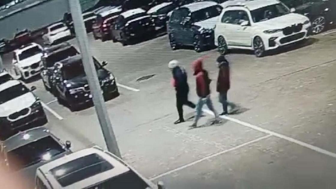 Три человека идут по парковке