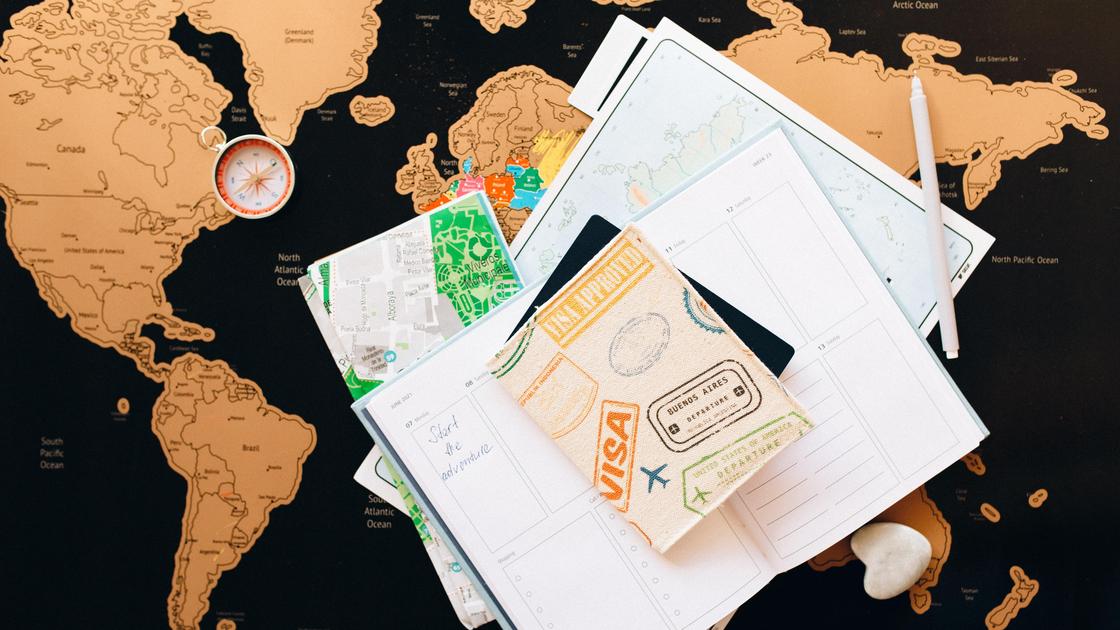 На карте мира лежит компас, документы и паспорт