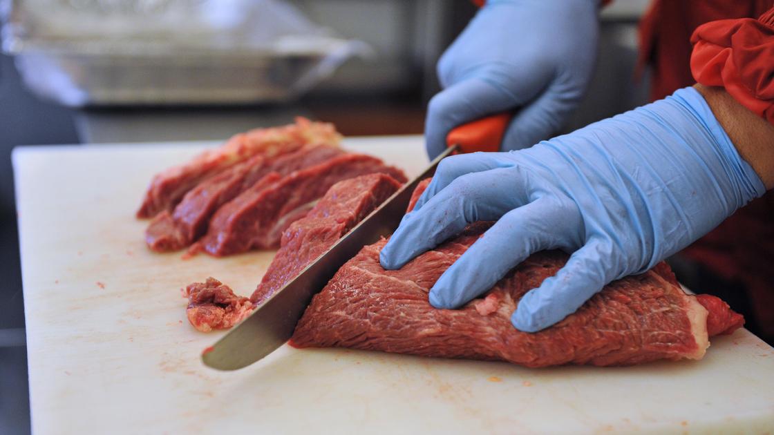 Продавец режет мясо