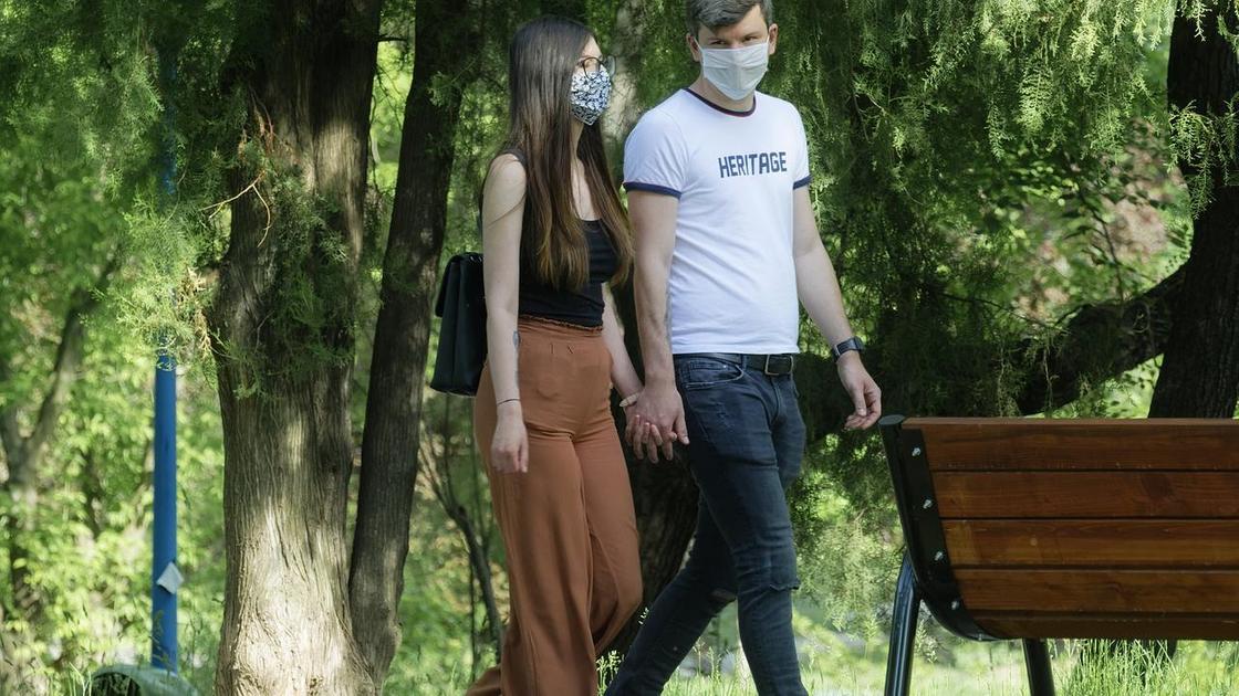 Пара прогуливается в защитных масках
