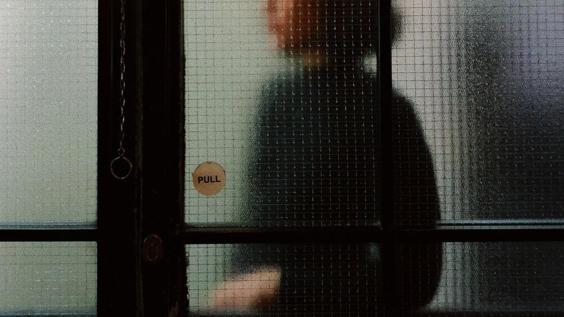 Девушка стоит за прозрачной витриной