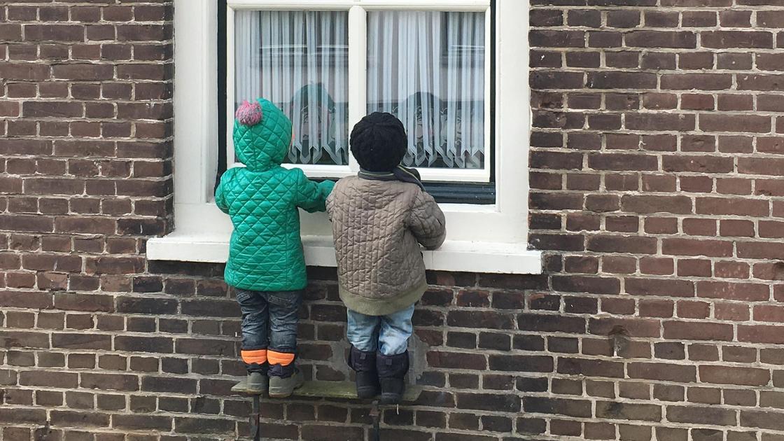 Двое детей смотрят в окно