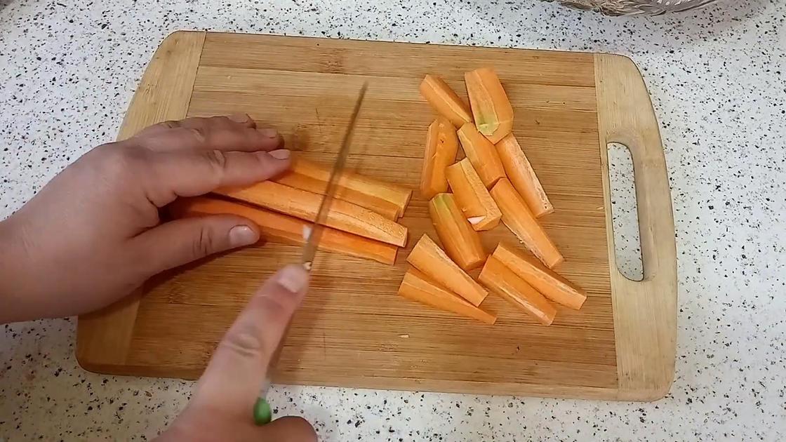 На разделочной доске крупно режут морковь