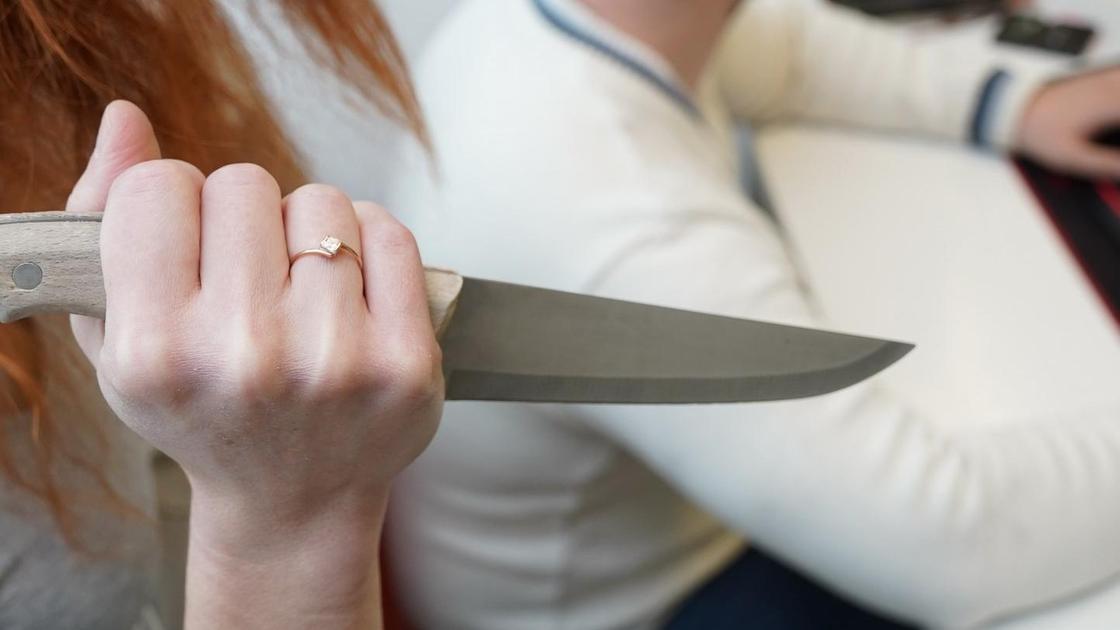 Женщина заносит нож над мужчиной