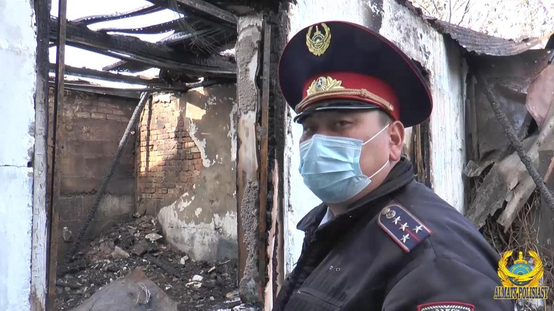 Полицейский стоит возле сгоревшего дома