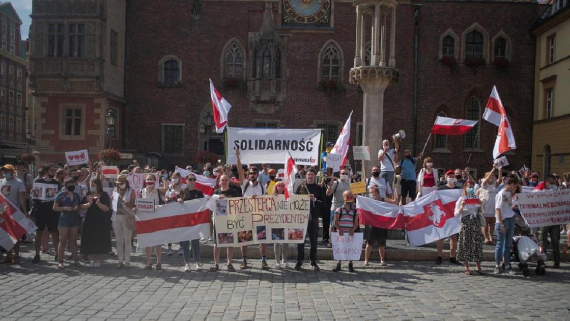 Протестующие в поддержку жителям Беларуси во Вроцлаве с флагами в руках