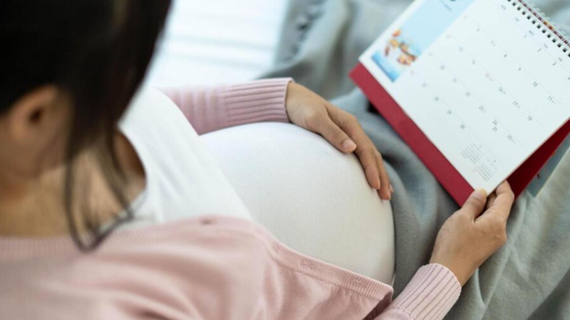 Беременная женщина с календарем на коленях
