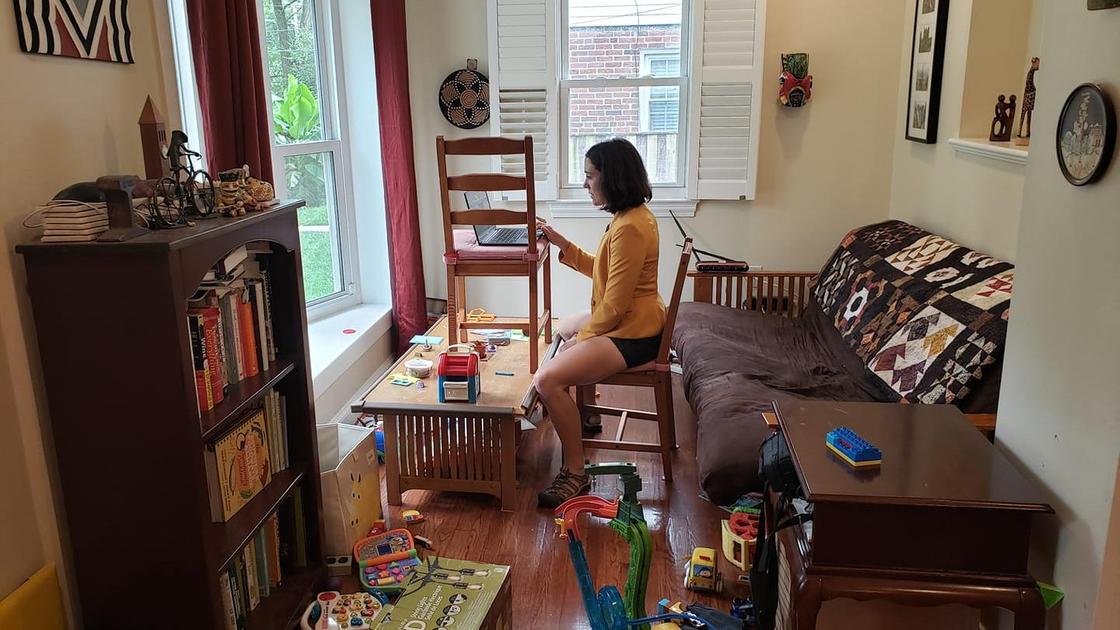 Женщина дает интервью онлайн в заваленной игрушками комнате