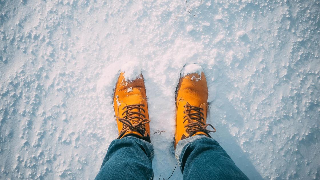 Человек в желтых ботинках стоит на снегу