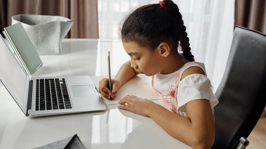 Девочка сидит за компьютером во время онлайн-урока
