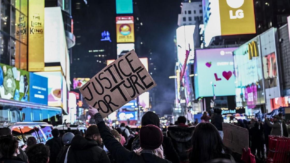 Толпа протестующих в Нью-Йорке и мужчина с плакатом