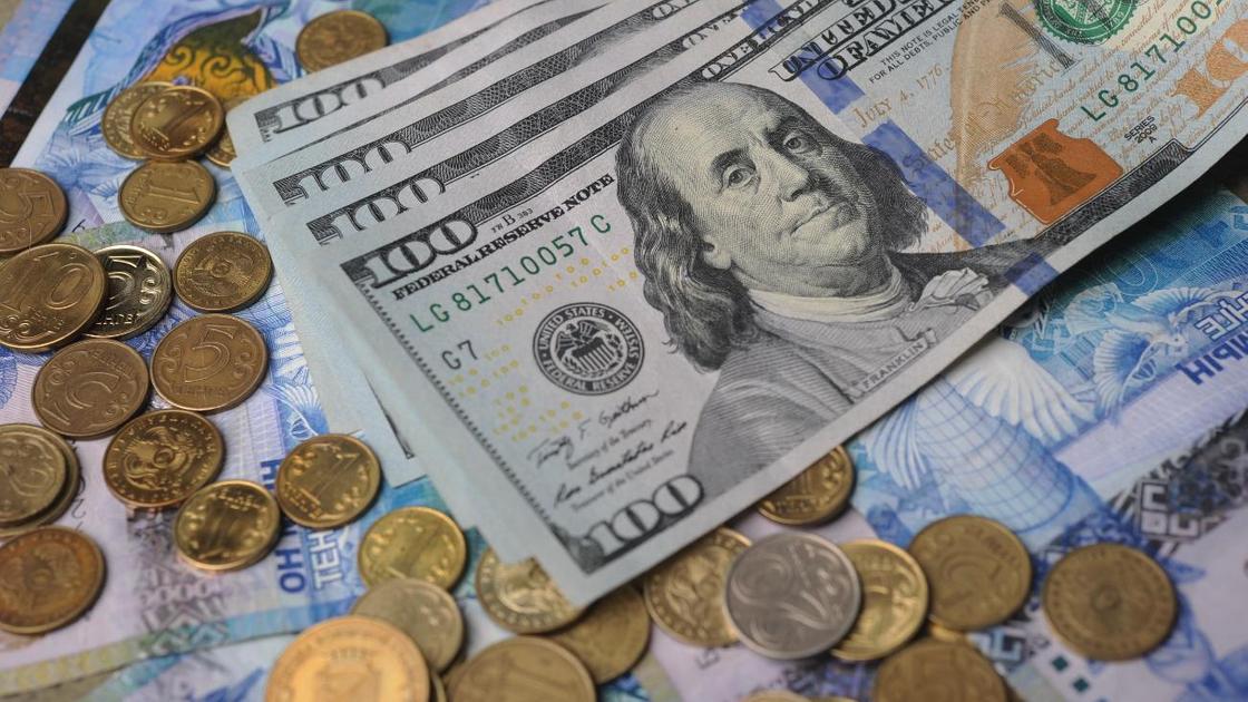 Долларовые банкноты лежат возле казахстанской валюты