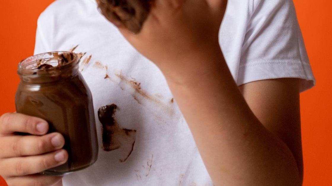 Ребенок ест арахисовое масло и оставляет жирные следы на футболке