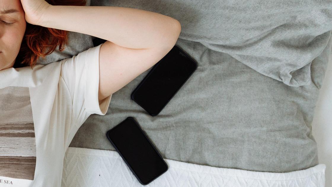 Смартфоны лежат на кровати возле женщины