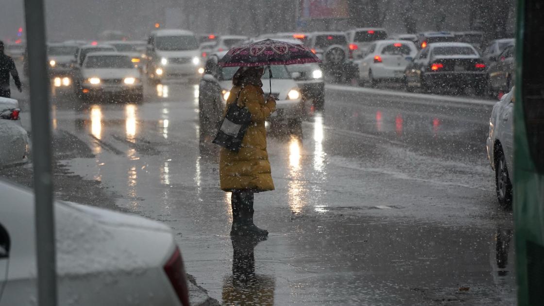 девушка с зонтом стоит под снегом на дороге