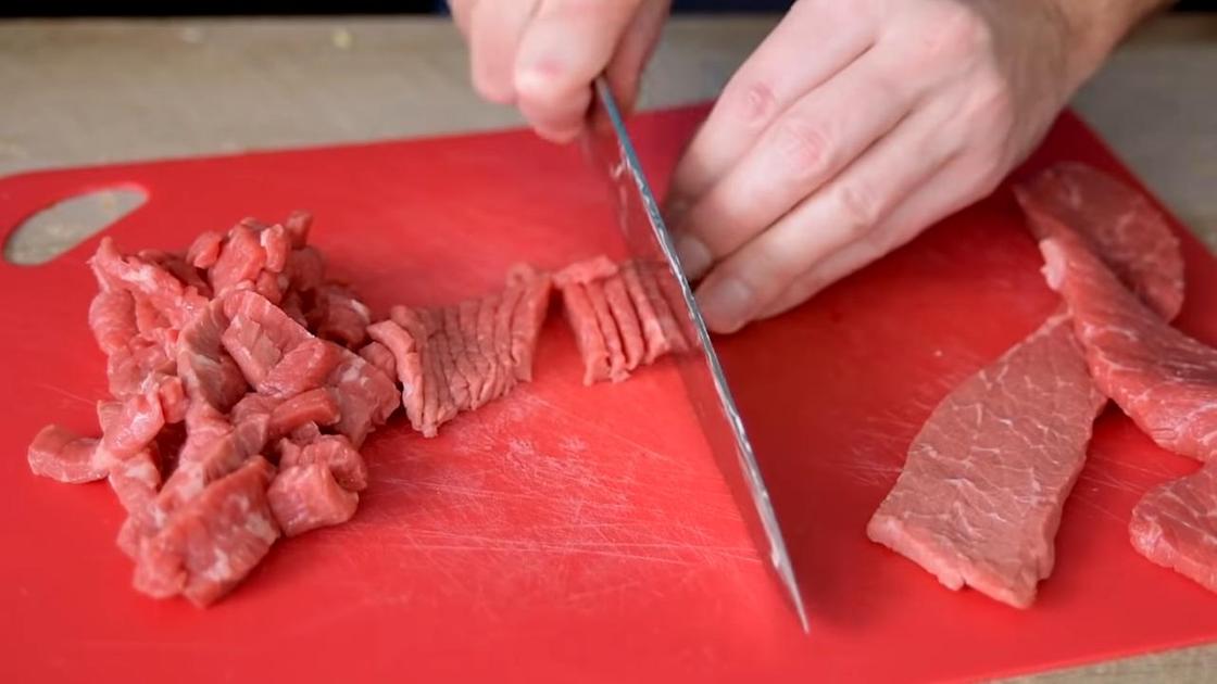 Нарезка стейков говядины соломкой на разделочной доске
